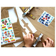 Paper plane craft kit for kids being assembled with cardboard airplanes and stickers