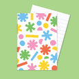 Small pocket notebook with colorful illustrations of shapes on the cover and lined paper inside.