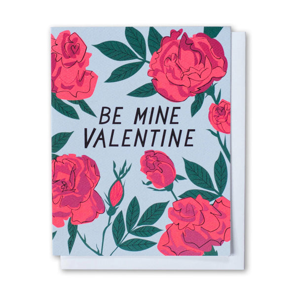 Greeting card with hand drawn letters that say "Be Mine Valentine" surrounded by illustrations of red roses on a blue background.