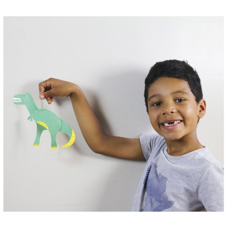 Child showing a paper dinosaur colored in by hand