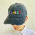 "Flowers" embroidered in large multi-colored letters on the front of a charcoal black ball cap 