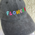 "Flowers" embroidered in large multi-colored letters on the front of a charcoal black ball cap