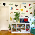 Wall decals with horses, leopards, cheetahs, sharks, whales, alligators, ghosts, strawberries and more on a wall in a home above a some books and a record player