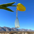 Gold ghost keychain hanging from a flower in the desert