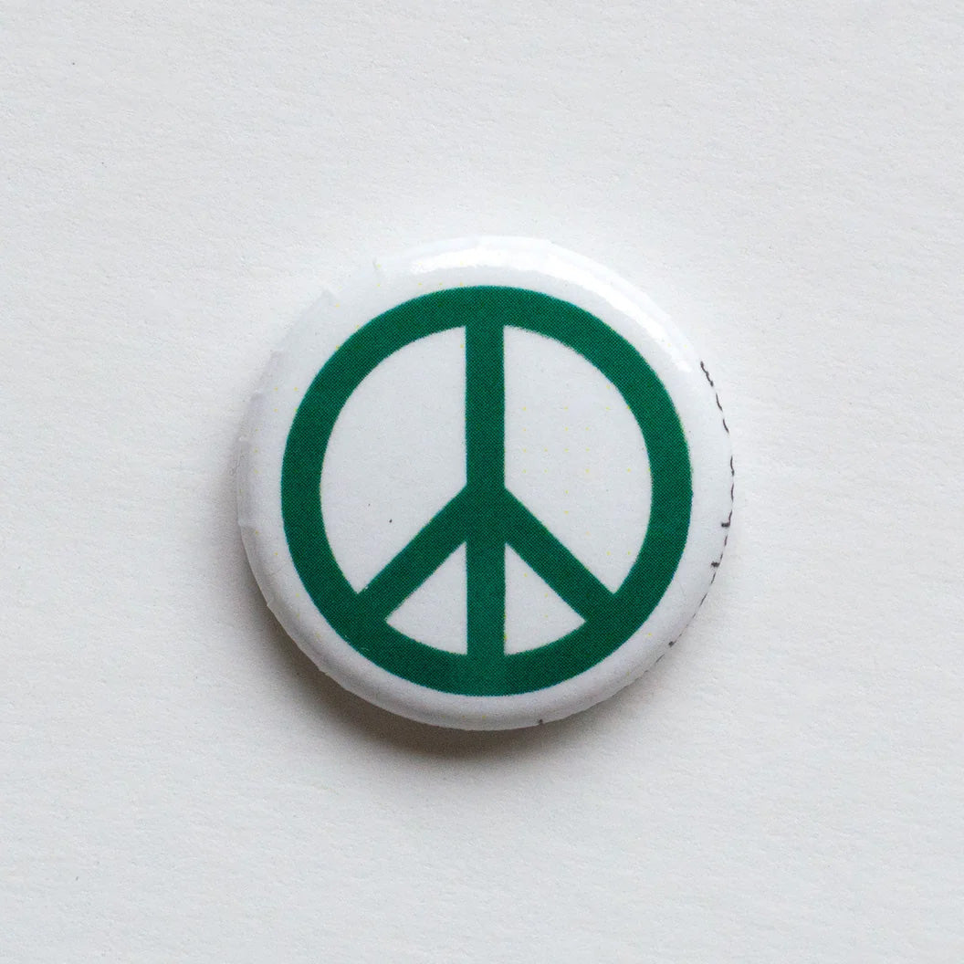 One inch button with green peace symbol on a white background