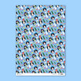 Gift wrap with illustrations of three penguins wearing winter hats holding a present, a candy cane and and an ice cream cone all on a bright blue background with stars, mushrooms and pine trees.