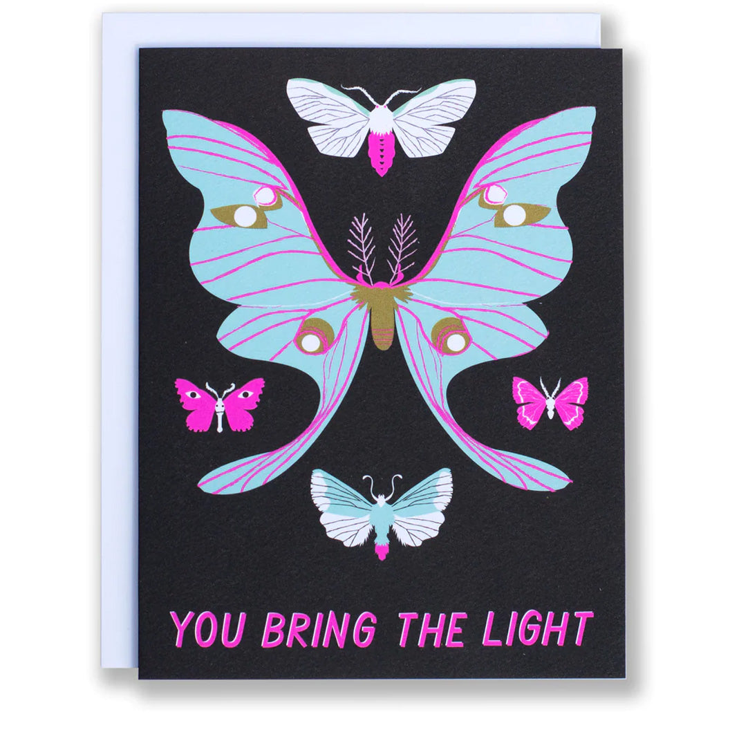 note card reads 'You Bring the Light' with a selection of moths in blue and neon pink on a black background