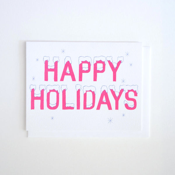 Greeting Card by Banquet with pink Happy Holidays lettering with snow on top on a white background