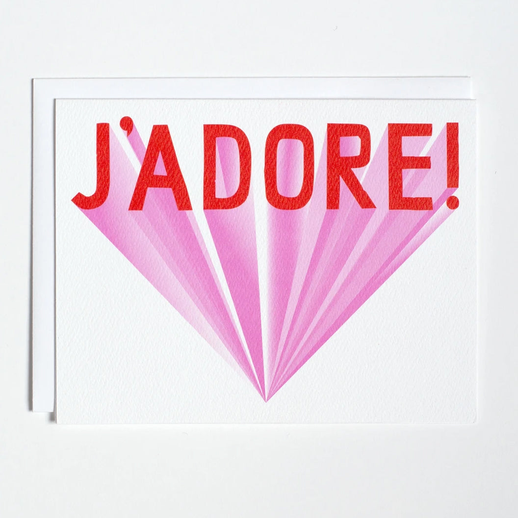 Greeting card with red lettering and pink backdrop that says J'Adore by Banquet Workshop