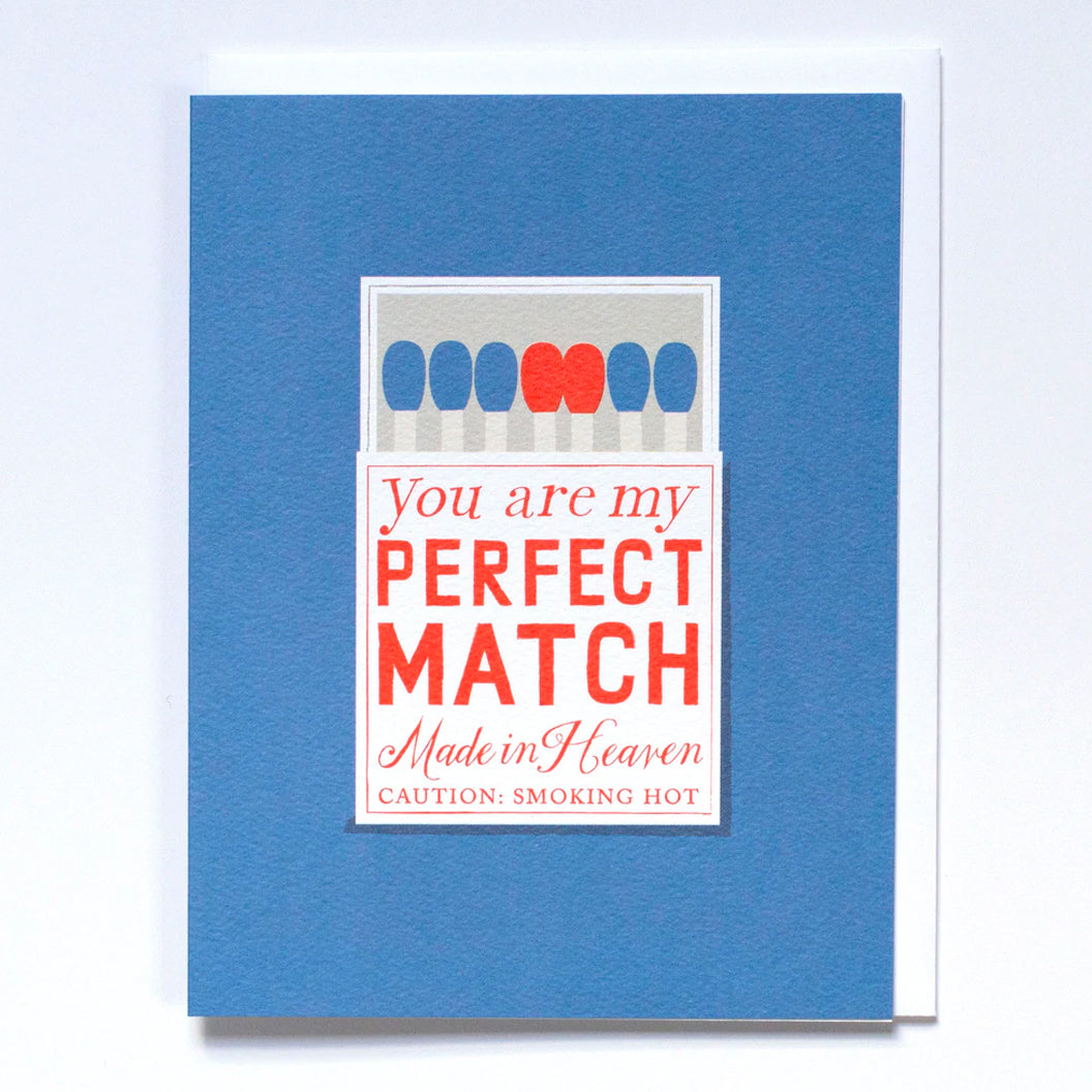 Greeting Card in Blue with an illustration of a matchbox that has "You are my perfect match made in heaven caution: smoking hot" in red lettering
