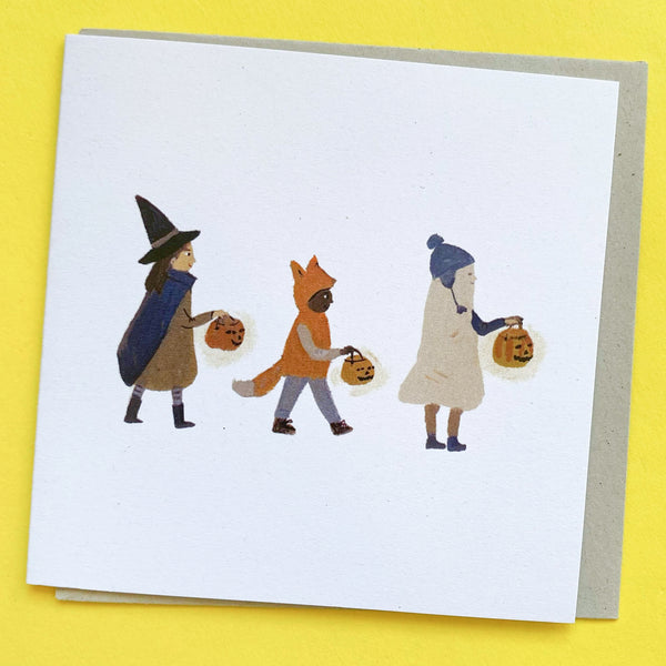 Halloween Friends Greeting Card with three small people dressed in costumes holding jack o'lanterns