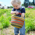 Child holding a handmade bolga basket at a farm