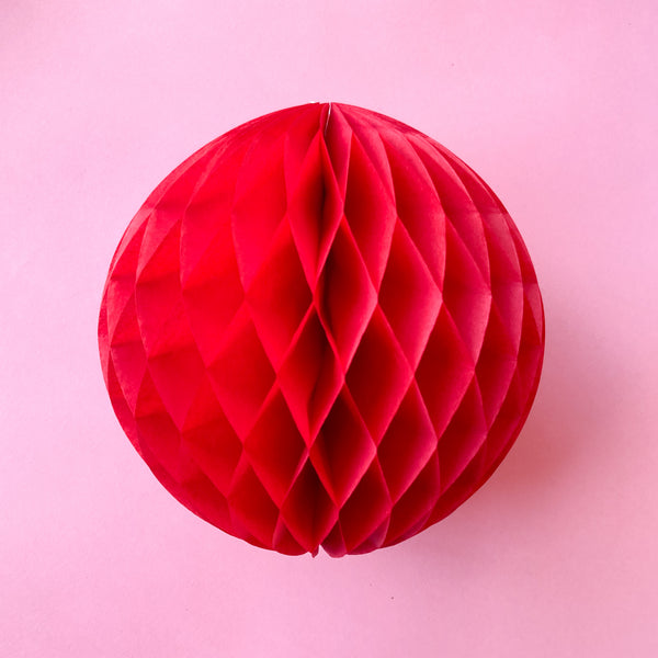 Paper honeycomb ball decoration in red and 8 inches across