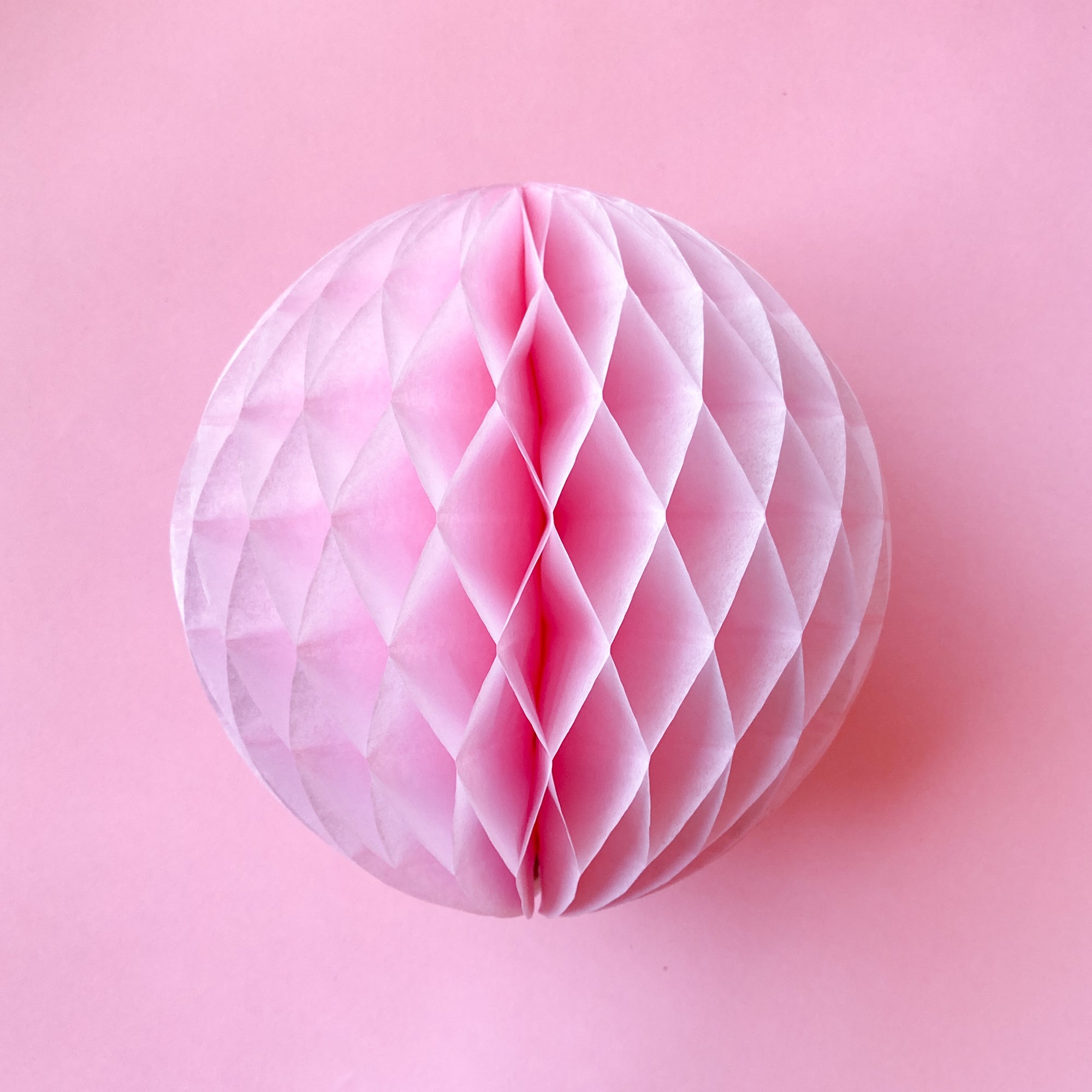 Paper honeycomb ball decoration in rose pink and 8 inches across