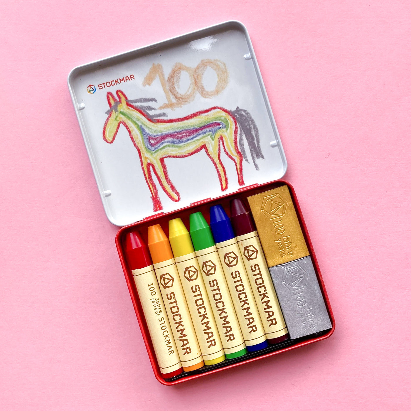 Six stockmar wax stick crayons and two block crayons in a tin case with the colours: carmine red, golden yellow, lemon yellow green, ultramarine, red violet, gold, silver