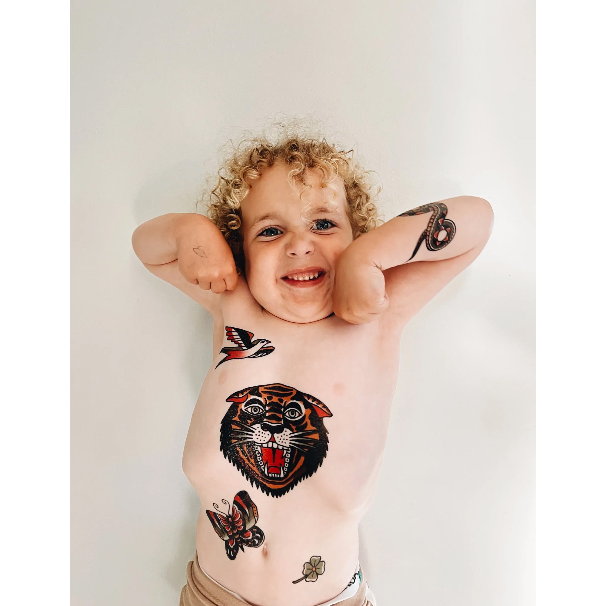 Young child with some temporary tattoos of a tiger, bird, butterfly and more